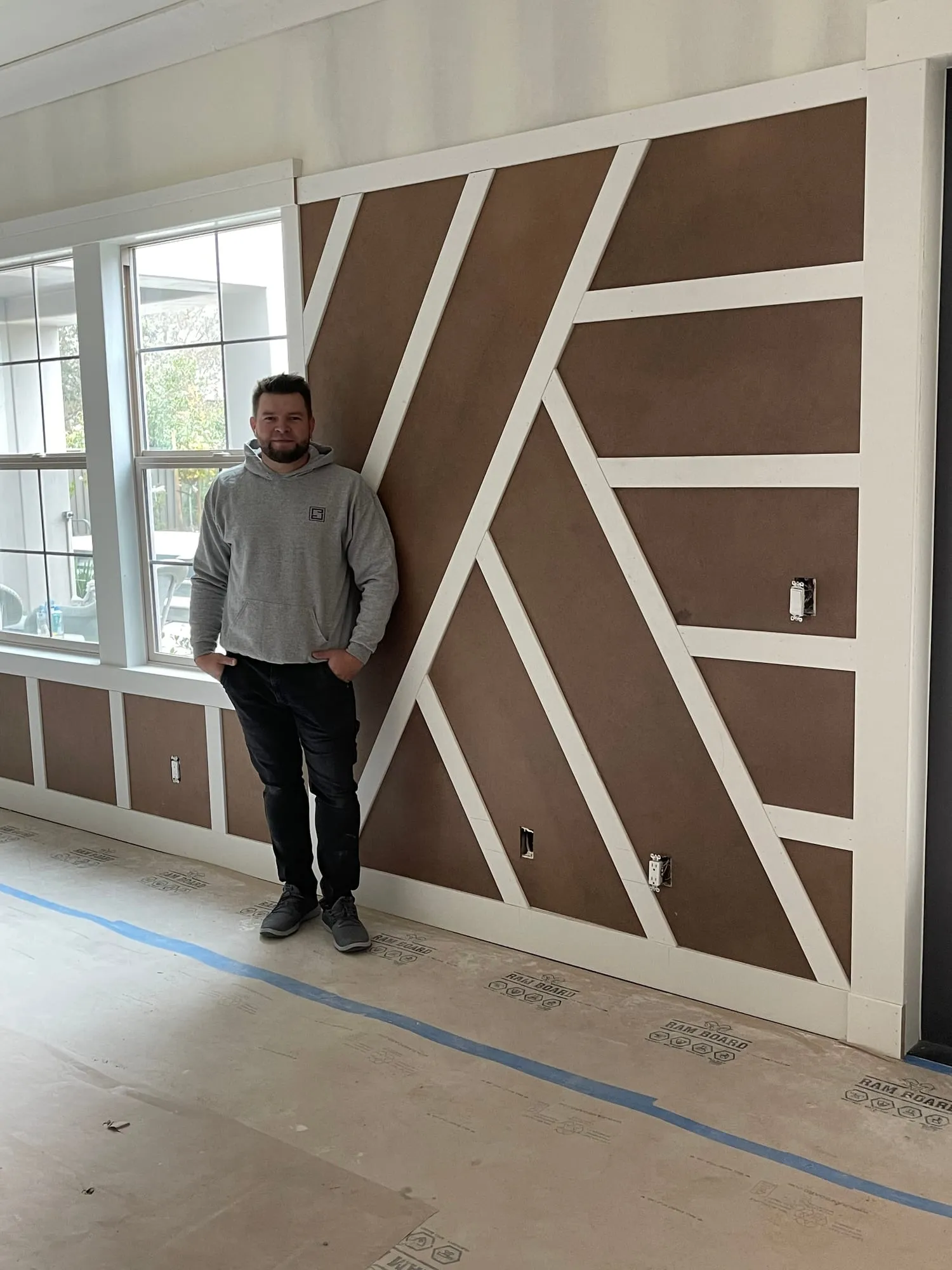 Maks Apanovich, owner of PrimeSpec Construction, in front of a custom accent wall